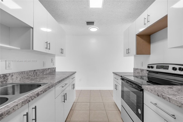 kitchen with light countertops, white cabinets, stainless steel range with electric cooktop, and visible vents