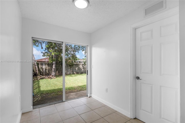 entryway featuring light tile patterned floors, baseboards, visible vents, and a textured ceiling