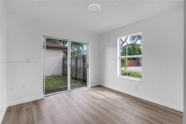 empty room with plenty of natural light, a textured ceiling, and wood finished floors