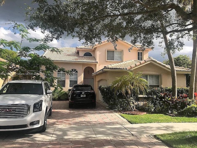 mediterranean / spanish house with decorative driveway, a tile roof, and stucco siding