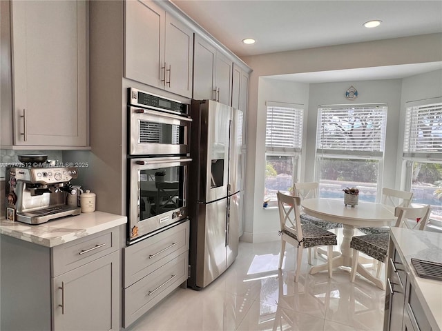 kitchen with light tile patterned floors, light stone countertops, gray cabinets, stainless steel appliances, and recessed lighting