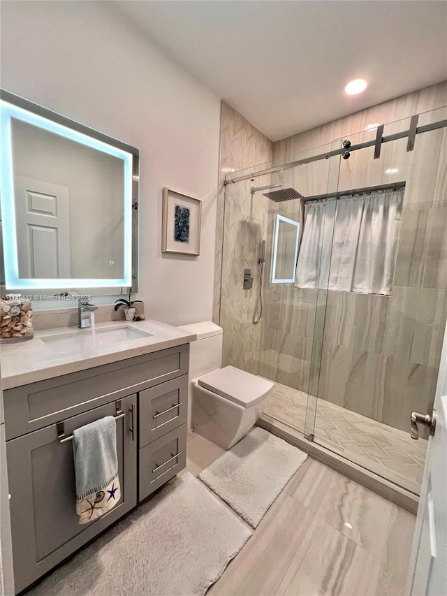 bathroom featuring toilet, a stall shower, and vanity