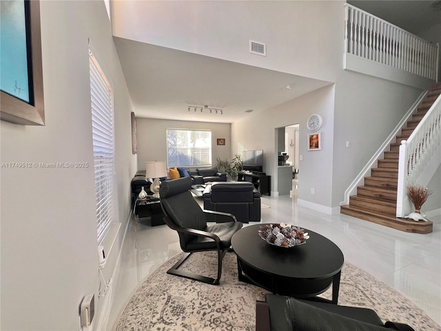 living area featuring a high ceiling, visible vents, baseboards, stairs, and marble finish floor