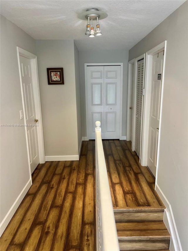 corridor featuring baseboards and dark wood finished floors