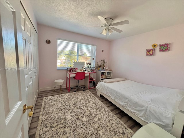 bedroom featuring a closet, ceiling fan, a textured ceiling, wood finished floors, and baseboards