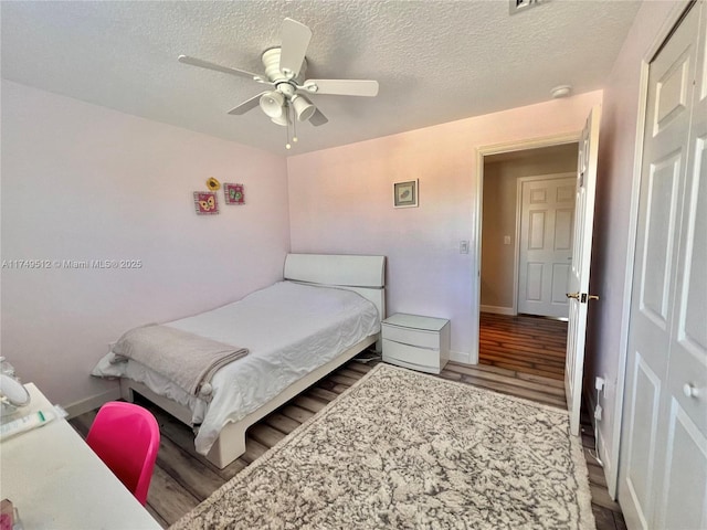 bedroom featuring ceiling fan, a textured ceiling, wood finished floors, and baseboards