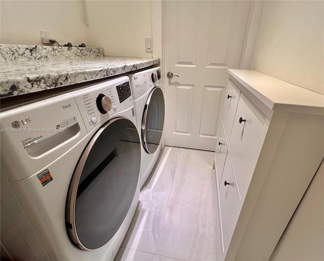 clothes washing area with washing machine and dryer and cabinet space