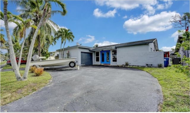 view of front of home featuring driveway, a front lawn, and an attached garage