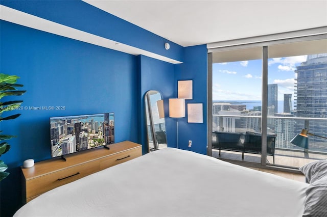 bedroom featuring a view of city and a wall of windows