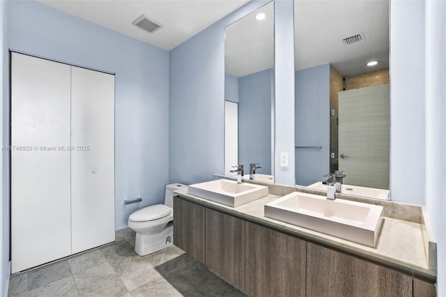 full bathroom with visible vents, a sink, toilet, and double vanity