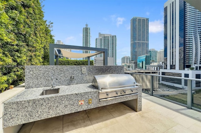 view of patio featuring a view of city, an outdoor kitchen, a sink, and area for grilling