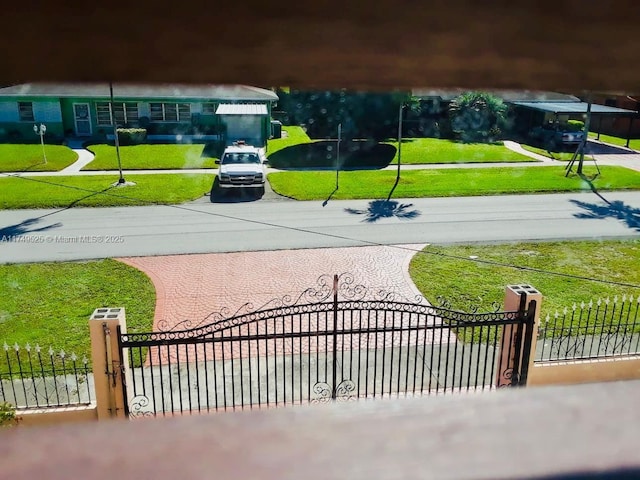 view of home's community with a fenced front yard, a gate, a lawn, and decorative driveway