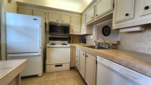 kitchen featuring white appliances, tile counters, decorative backsplash, cream cabinets, and a sink