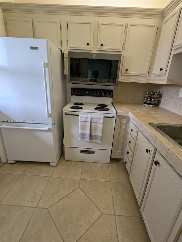 kitchen featuring tasteful backsplash, white electric stove, tile counters, stainless steel microwave, and designer fridge