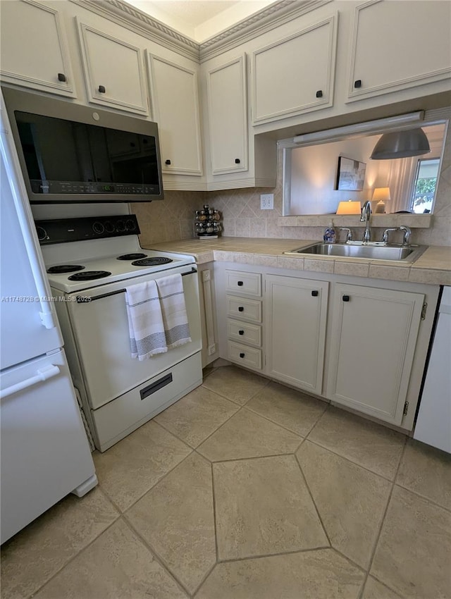 kitchen with white appliances, white cabinets, a sink, light countertops, and backsplash