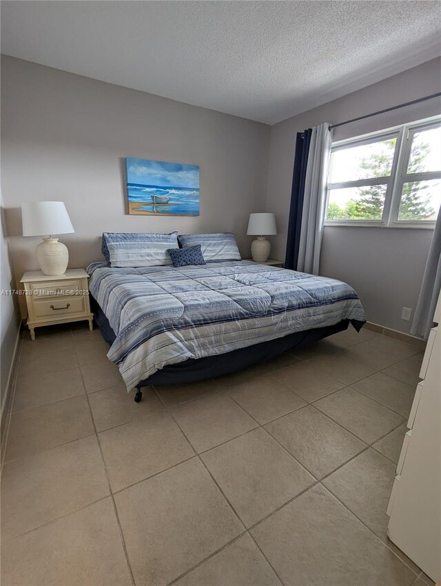 bedroom featuring light tile patterned flooring, a textured ceiling, and baseboards