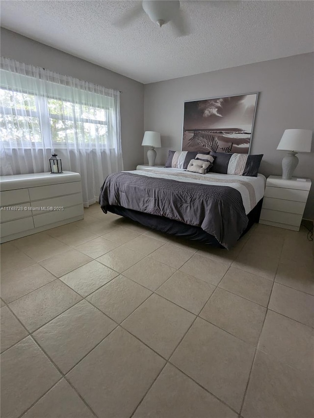 bedroom with a textured ceiling, light tile patterned flooring, and a ceiling fan