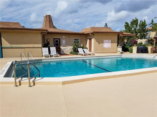 community pool featuring a patio and area for grilling