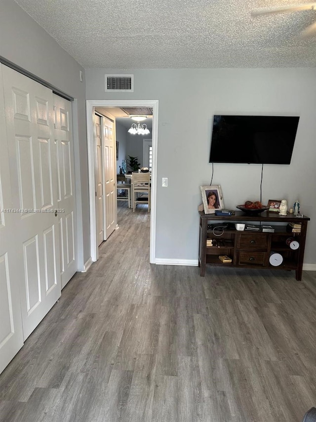 living area featuring baseboards, a textured ceiling, visible vents, and wood finished floors