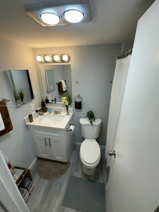 full bathroom with wood finished floors, vanity, toilet, and baseboards