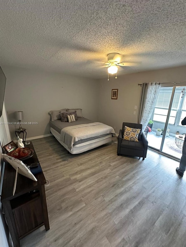 bedroom with access to exterior, ceiling fan, a textured ceiling, wood finished floors, and baseboards