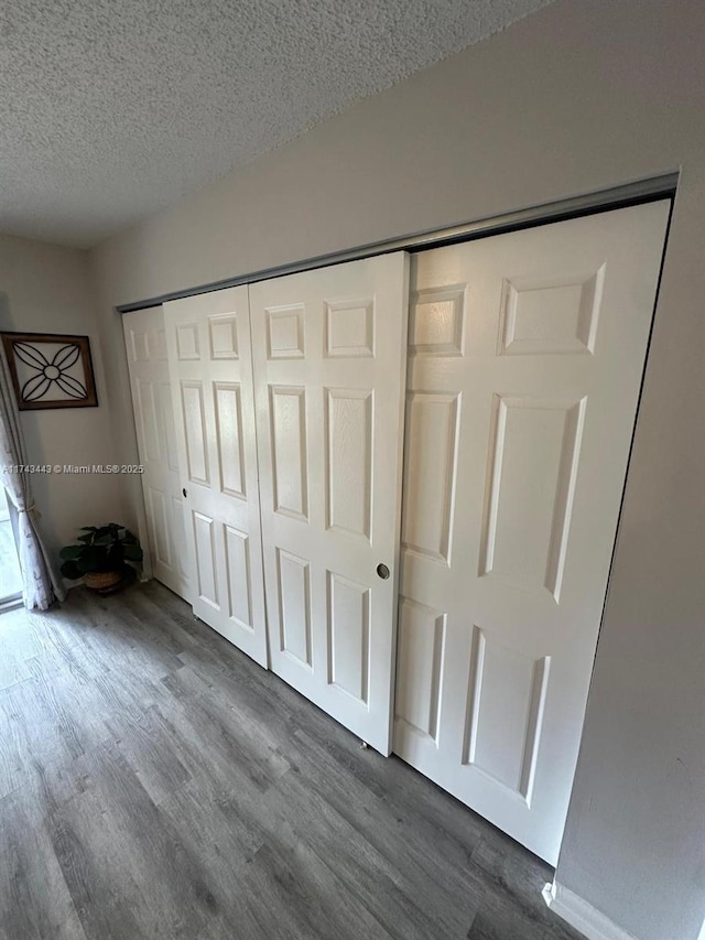 unfurnished bedroom featuring a textured ceiling, a closet, and dark wood finished floors