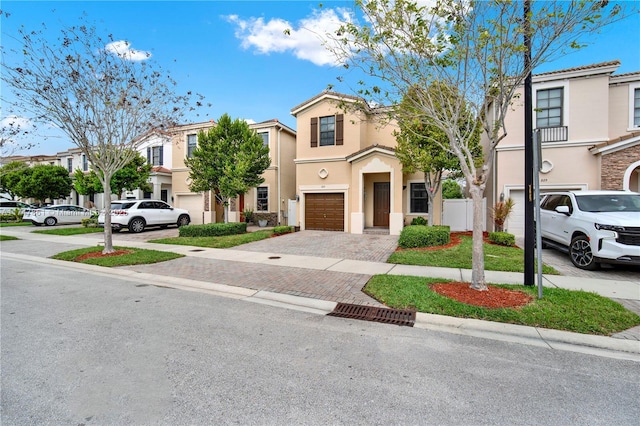 multi unit property with decorative driveway, an attached garage, a residential view, and stucco siding