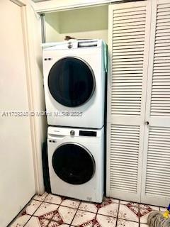 clothes washing area featuring stacked washer and dryer, laundry area, and light tile patterned floors