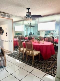 tiled dining room featuring a textured ceiling and a ceiling fan