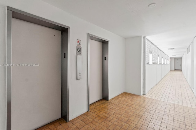 hall featuring brick patterned floor and elevator