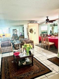 living area with light tile patterned flooring, ceiling fan, and a textured ceiling