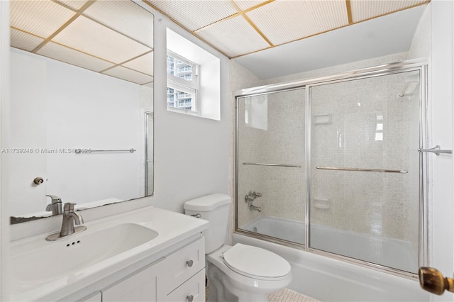 bathroom with toilet, vanity, and combined bath / shower with glass door