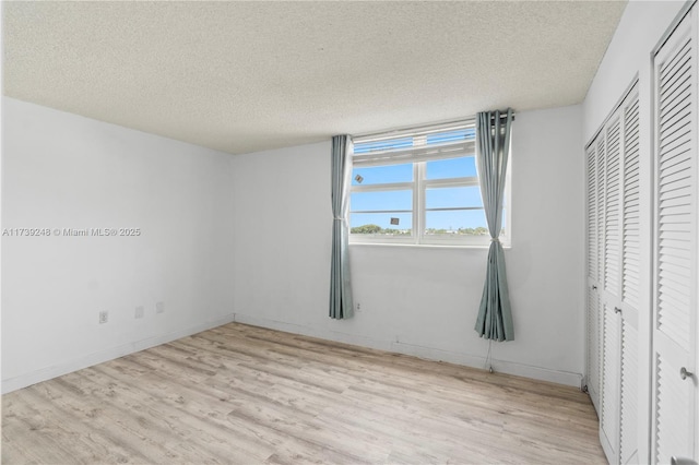 unfurnished bedroom with wood finished floors, a textured ceiling, and a closet