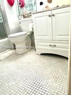 bathroom featuring toilet, shower / bath combination with glass door, and tile patterned flooring