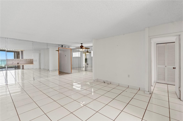 spare room with ceiling fan, a textured ceiling, visible vents, and light tile patterned floors