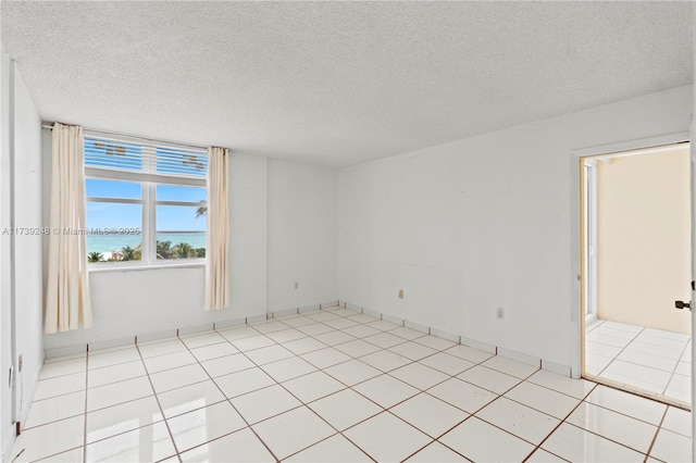 spare room featuring a textured ceiling and a water view