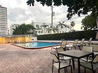 community pool featuring a view of city, a patio area, and fence