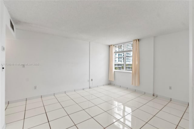 unfurnished room featuring light tile patterned flooring, a textured ceiling, and visible vents