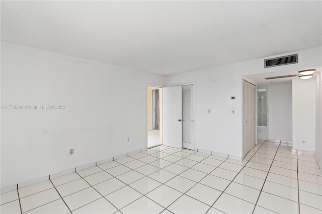 spare room featuring baseboards, visible vents, and light tile patterned floors