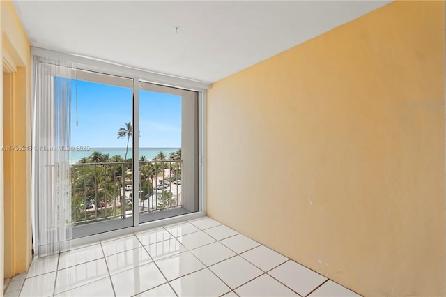 empty room featuring floor to ceiling windows, a water view, and light tile patterned flooring