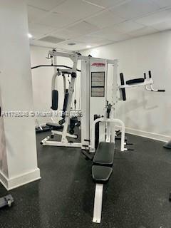 workout area featuring a drop ceiling and baseboards