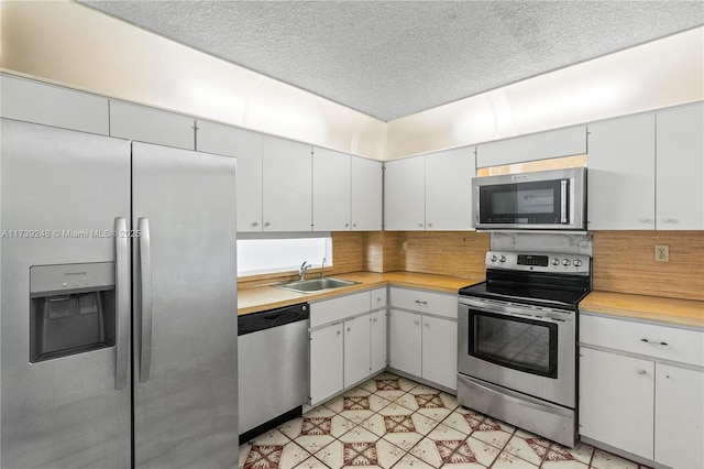 kitchen with light countertops, decorative backsplash, stainless steel appliances, and a sink