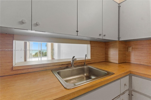 kitchen with light countertops, a sink, backsplash, and white cabinetry
