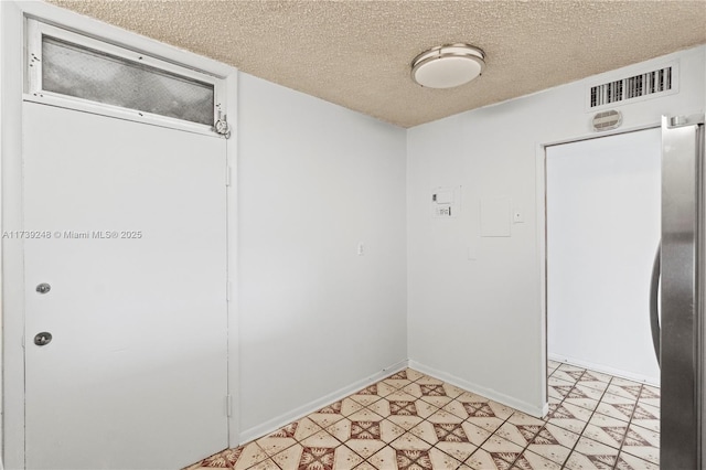 spare room with baseboards, visible vents, and a textured ceiling