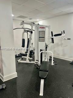 gym featuring a drop ceiling and baseboards