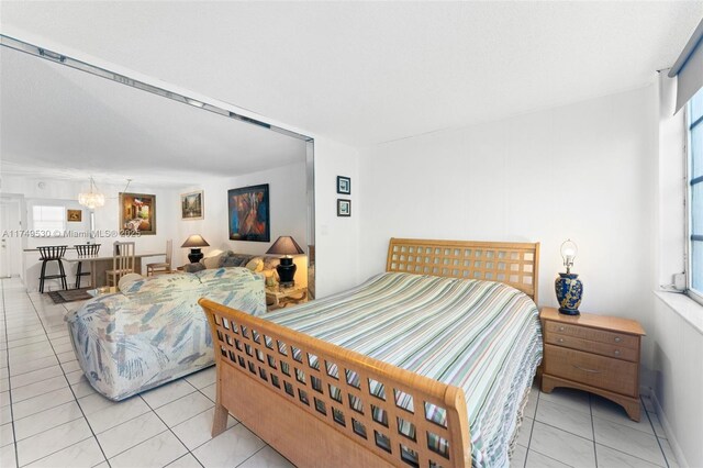 445 NE 195th St Unit 324, Miami, FL 33179 - bedroom with light tile patterned floors and an inviting chandelier