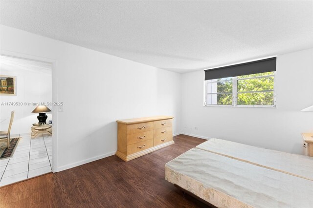 445 NE 195th St Unit 324, Miami, FL 33179 - bedroom with dark wood-type flooring, a textured ceiling, and baseboards
