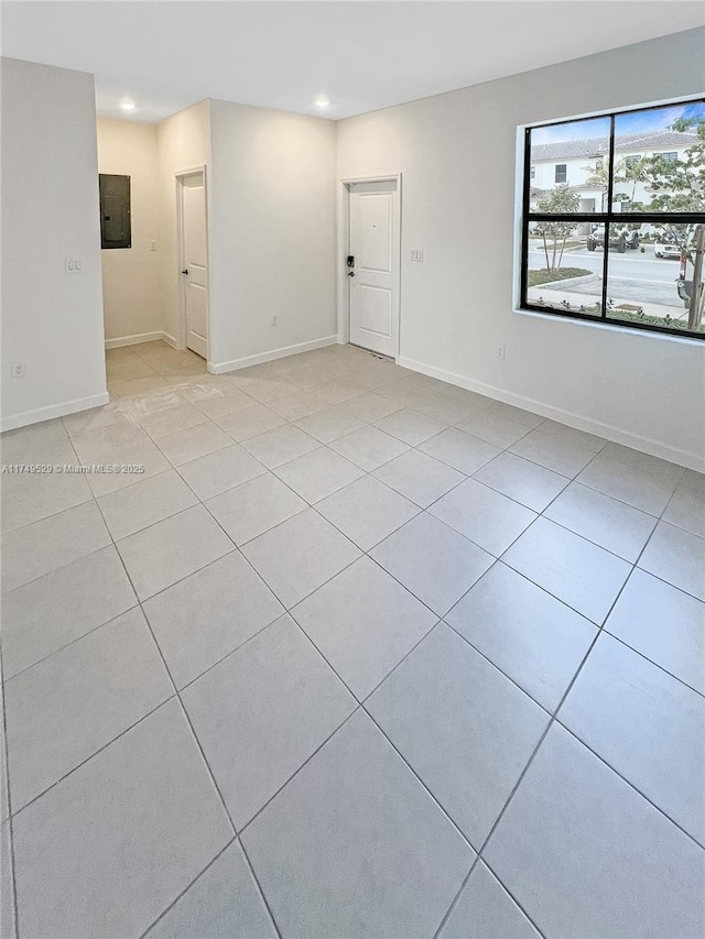 spare room featuring light tile patterned floors, recessed lighting, electric panel, and baseboards