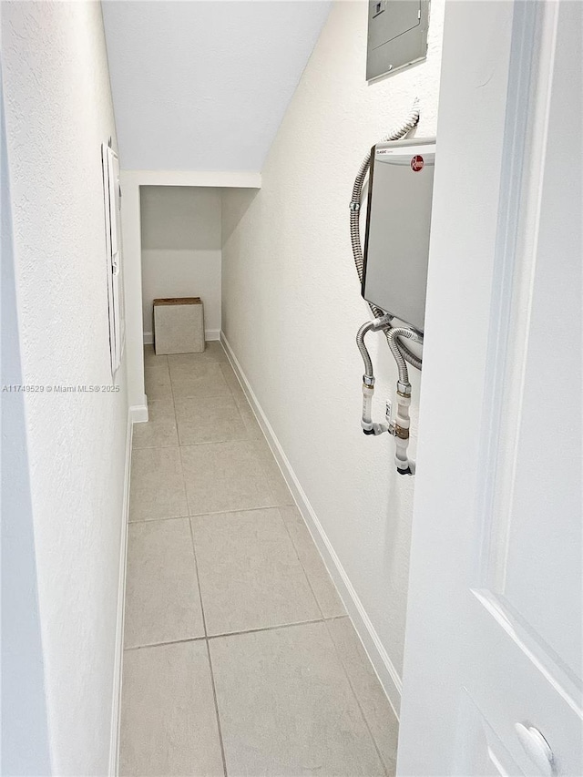 hallway with light tile patterned floors, vaulted ceiling, electric panel, and baseboards