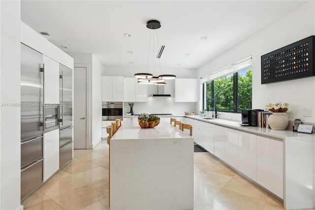 kitchen featuring modern cabinets, a center island, decorative light fixtures, light countertops, and white cabinetry